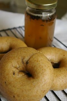 three donuts sitting on a cooling rack next to a jar of honey