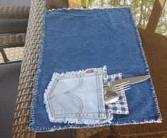 a pair of scissors sitting in the pocket of an old jean table cloth that has been folded over