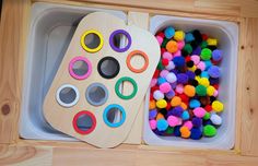 two trays with different colored pom - poms in them