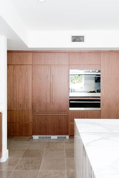 an empty kitchen with marble counter tops and wooden cabinetry, along with stainless steel appliances