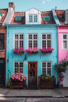 a blue building with pink flowers on the windows