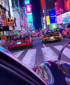 cars driving down the street in times square at night with neon signs and billboards