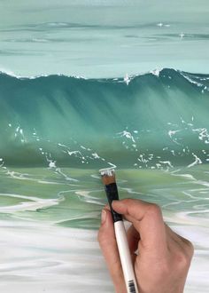 a painting of a hand holding a brush in front of an ocean wave