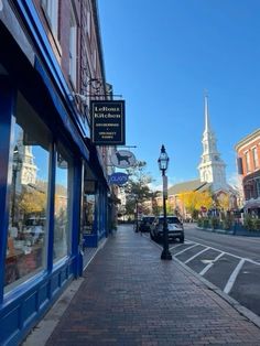 an empty sidewalk in front of a building on a city street with tall spires