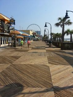 the boardwalk is lined with shops and palm trees