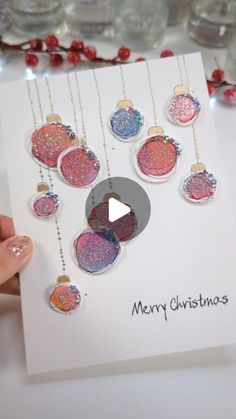 someone holding up a christmas card with ornaments on it