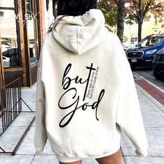 a woman walking down the street wearing a white hoodie that says, but god