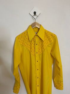 Vintage western button up shirt This western shirt is absolutely gorgeous! With floral design near the collar and yellow throughout it is just an amazing piece From my research this shirt is from the 1950s or 1960s has gorgeous glass red buttons and all the details are nearly perfect condition No holes and only one small mark from dust This shirt fits like a women's medium Fitted Yellow Shirt For Fall, Yellow Fitted Shirt For Fall, Vintage Button-up Shirt For Rodeo, Vintage Collared Shirt For Rodeo, Fitted Yellow Shirt With Buttons, Vintage Collared Tops For Rodeo, Fitted Yellow Shirt With Button Closure, Retro Collared Tops For Rodeo, Retro Long Sleeve Yellow Shirt