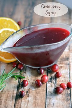 cranberry syrup in a glass bowl next to oranges and rosemary