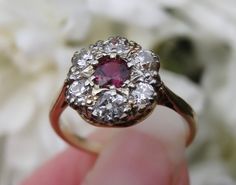 Free shipping and complementary resize*! This gorgeous ring is designed with a central cherry natural ruby set within a surround of eight smaller diamond 'petals'. The .5 carat ruby is exceptional in colour, and has incredible clarity. The sparkling old cut diamonds total 0.78 carat. Rubies are arguably one of the rarest gem stones on earth and an antique ruby with old cut diamonds (set in this design) is particularly coveted by collectors and brides alike.... You'll struggle to find another. Go Classic Ruby Ring With Rose Cut Diamond Cluster, Cluster Ruby Ring With Rose Cut Diamonds, Red Diamond Cluster Ring With Halo Setting, Cluster Ruby Diamond Ring With Center Stone, Ruby Cluster Ring With Rose Cut Diamonds, Round Ruby Cluster Ring With Rose Cut Diamonds, Red Ruby Cluster Ring With Rose Cut Diamonds, Cluster Ruby Ring With Center Stone, Classic Cluster Ruby Ring