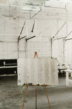 an easel with a sign on it in a room filled with tables and chairs