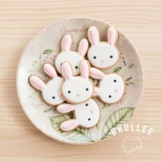 three decorated cookies in the shape of bunnies on a plate with leaves and flowers