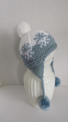 a knitted hat with pom - poms sits on top of a mannequin's head