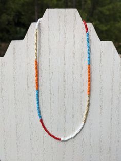 "This delicate ~16 inch necklace is the perfect complement to your favorite sweater, or a unique statement piece for Halloween, Thanksgiving, or any other day of the year. It was handmade with gold, red, orange, white, and light blue glass seed beads, and finished with a ~3 inch silver-toned adjustable necklace chain, lobster clasp closure, crimp beads, and jump rings.  This piece has the flexibility to act as a standalone item or as a layer in a necklace set you already own. All BullCityBeadworks necklaces are crafted with Beadalon 7-Strand 0.012\" (0.30 mm) Bright Bead Stringing Wire, which is made of stainless steel and is abrasion-resistant. I hope you enjoy my pieces as much as I loved making them! In order to maintain their quality and color, please handle with care and keep dry. If Red Letter Beads Festival Jewelry, Red Beaded Necklace With Letter Beads For Jewelry Making, Orange Necklace With Letter Beads For Gifts, Red Necklaces With Round Letter Beads, Red Beach Necklace With Spacer Beads, Adjustable Red Necklace With Letter Beads, Red Bohemian Jewelry With Letter Beads, Red Bohemian Necklace With Letter Beads, Bohemian Red Jewelry With Letter Beads