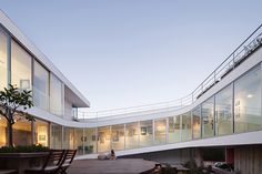 two people sitting on benches in front of a building with glass walls and balconies