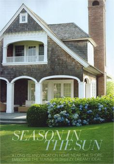 a brick house with white trim and blue hydrangeas