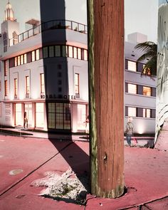 a wooden pole sitting on the side of a road next to a tall white building