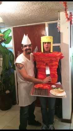 two men in costumes are holding a cake