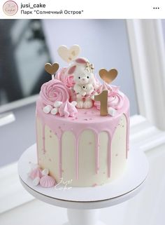 a pink and white cake with teddy bear on top