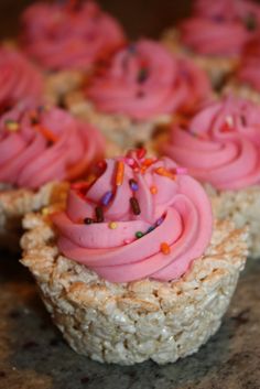 cupcakes with pink frosting and sprinkles on them sitting on a table