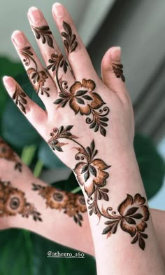 the hands are decorated with henna designs and flowers on their palms, as well as palm leaves