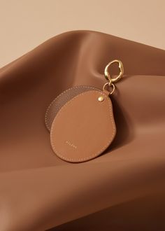 a brown leather bag with a gold keychain hanging from it's side