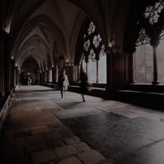 a person is walking in an old building with stone flooring and large arched windows