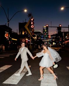 a bride and groom crossing the street at night in las vegas, nv on their wedding day