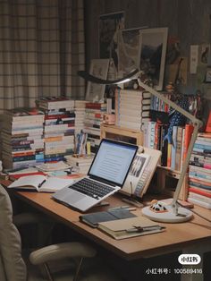 a laptop computer sitting on top of a wooden desk next to a pile of books