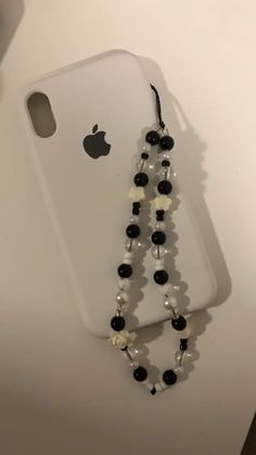 a cell phone with a black and white beaded necklace attached to the back of it