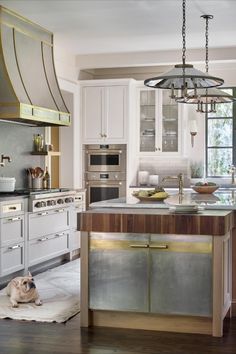 a dog laying on the kitchen floor in front of an island and stove top oven