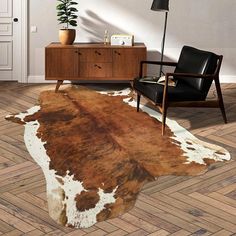 a cowhide rug in the middle of a living room with a chair and table