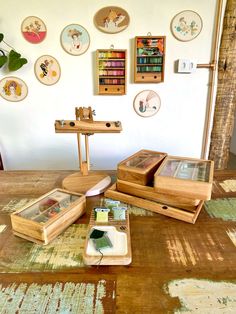 there are several wooden boxes on the floor in front of some wall hangings with pictures