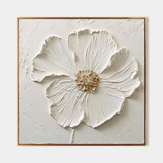 a large white flower mounted to the side of a wall in front of a gold frame