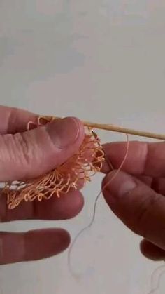 two hands are working on an object with yarn