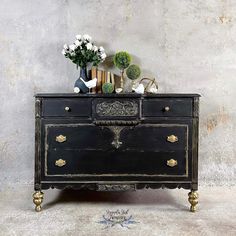 an old dresser with flowers and books on top, against a gray concrete wall background