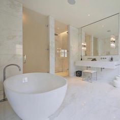 a large white bath tub sitting next to a sink in a bathroom under a mirror