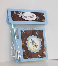 two blue and brown notepads with flowers on them, one has a pen in it