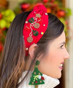 a woman wearing a red headband with christmas decorations on it and a green tree