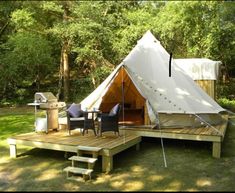 a teepee tent is set up on a deck in the middle of a wooded area