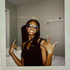 a woman wearing sunglasses making the peace sign