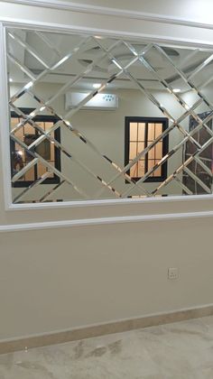 a mirror reflecting the reflection of two windows in a room with white walls and marble flooring