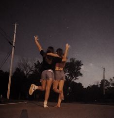 two girls jumping in the air with their arms around each other on a skateboard