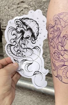 a person holding up a sticker with an octopus tattoo on it's arm