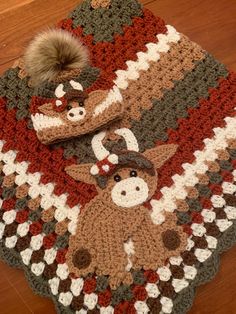 a crocheted blanket with a deer and moose design on it sitting on a wooden floor