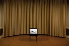 a television sitting on top of a stand in front of a curtained wall and floor