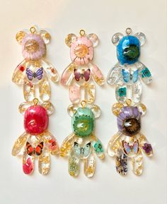 four different colored teddy bears sitting next to each other on top of a white surface