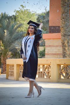 a woman in graduation gown throwing confetti into the air