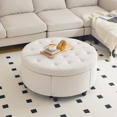 a living room with a couch, ottoman and coffee table on the floor in front of it