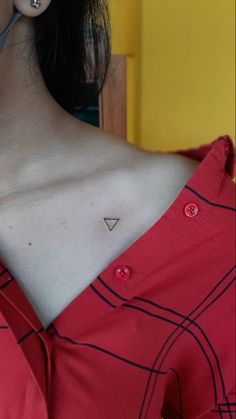 a woman with a small triangle tattoo on her chest is looking at the camera while wearing a red dress